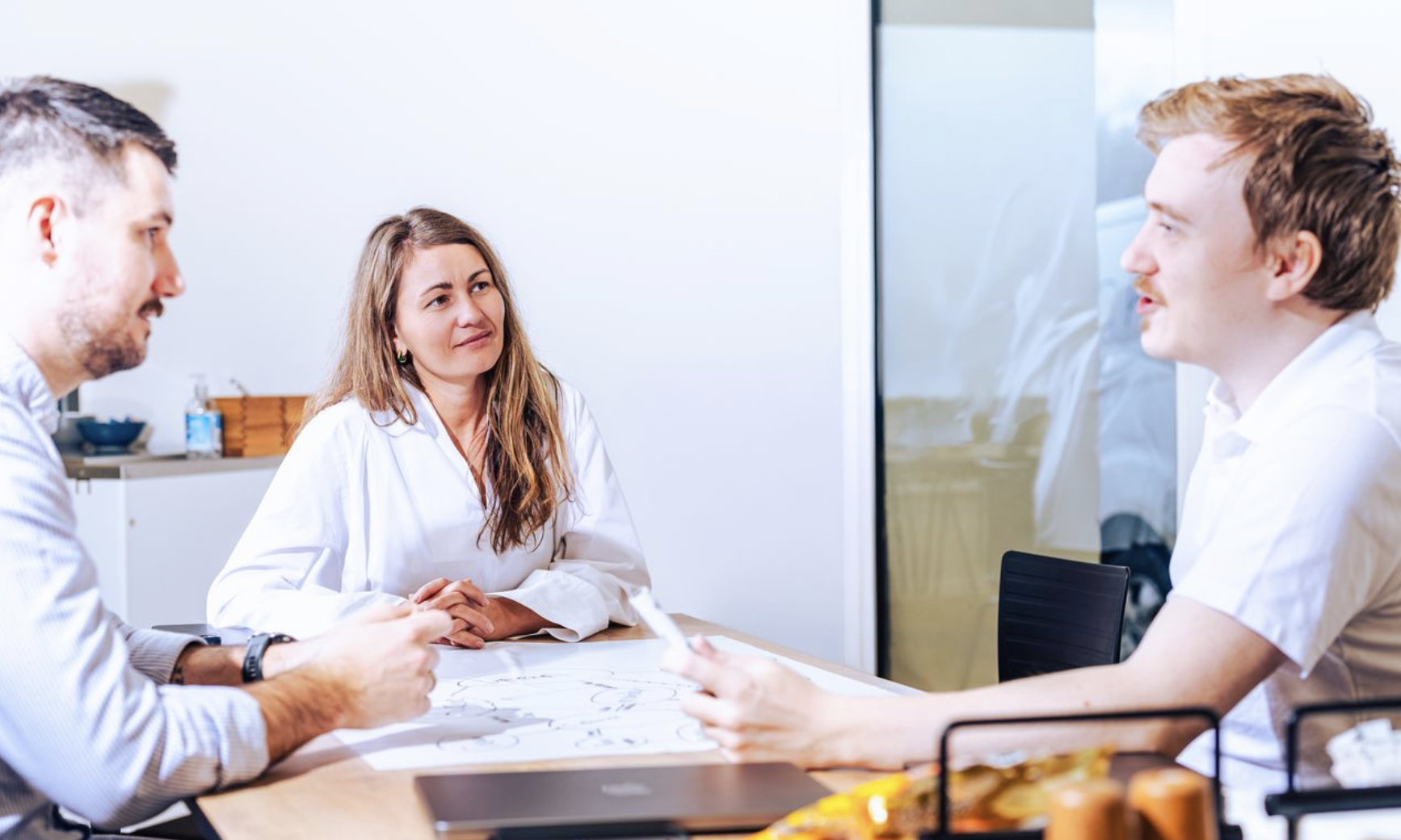 The image shows three UNIwise employees in a meeting situation