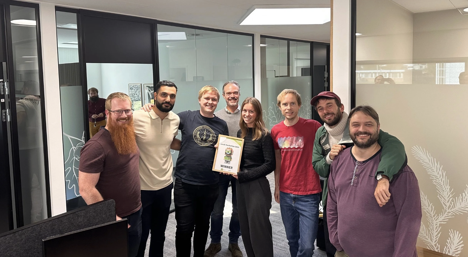 Participants of the first UNIwise Hackathon stand together in an office, showcasing their partnership with Amazon Web Services and Nordic clients.