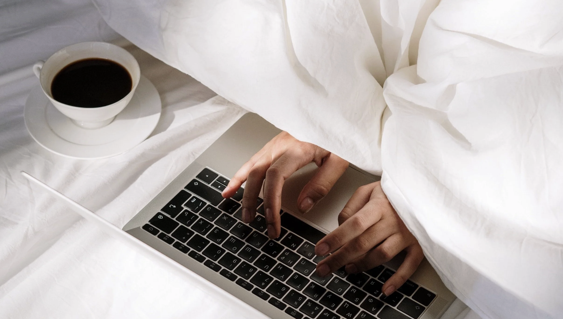 Student engaging with learning in bed in the morning with coffee and computer