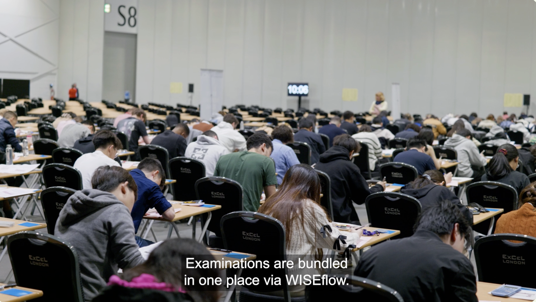 Students taking a pen and paper exam in a large exam hall
