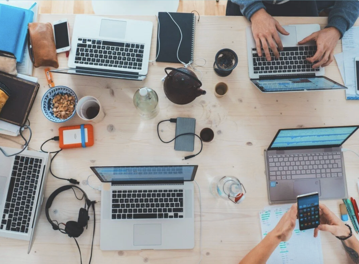 Image of computers and clutter on table with people working
